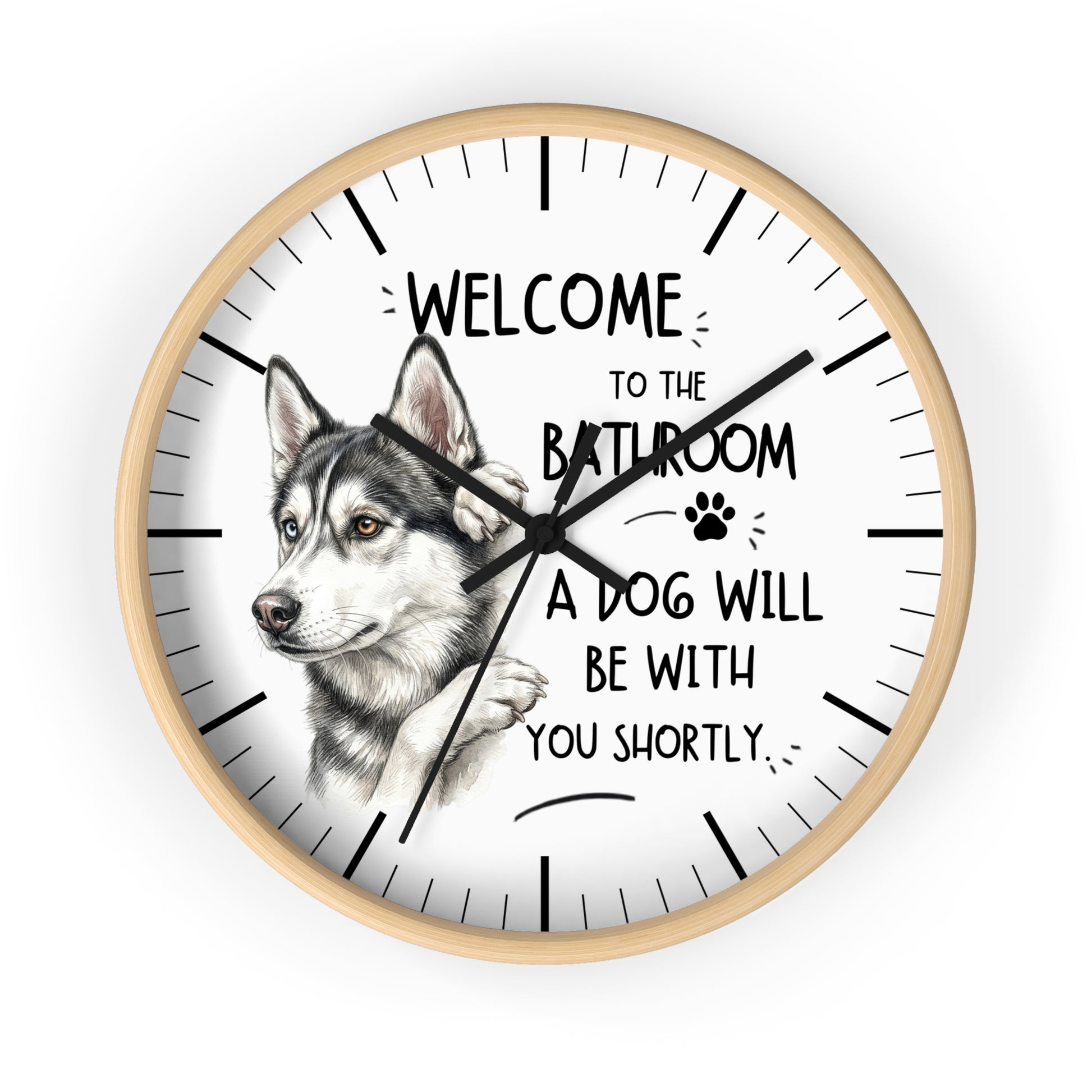 A round wall clock with a light wood frame and a white face, featuring a detailed illustration of a husky dog and the humorous text 'WELCOME TO THE BATHROOM A DOG WILL BE WITH YOU SHORTLY.'.