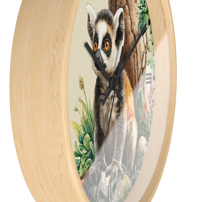 Round wall clock with a light natural wood frame and a printed center illustration of a lemur sitting on rocks beside a tree trunk, with black clock hands on a white background.