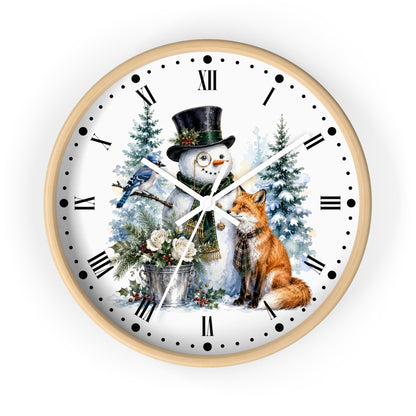 A round wall clock with a light wood frame and a white face featuring a winter holiday illustration of a snowman in a black top hat, a red fox, evergreen trees, a bird, and Roman numerals.