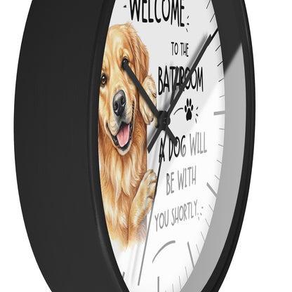 A round wall clock with a black frame and a white face featuring a golden retriever illustration and the text 'WELCOME TO THE BATROOM A DOG WILL BE WITH YOU SHORTLY'.