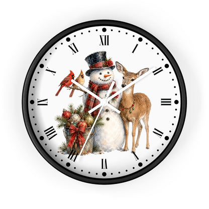 A round wall clock with a black frame and a white face featuring a Christmas illustration of a snowman, a deer, a red cardinal, and holiday greenery, with black Roman numerals and white hands.