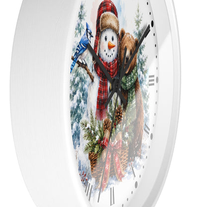 A white round wall clock featuring a festive winter illustration with a snowman in a red plaid scarf, a brown bear, a blue jay, pine trees, and black clock hands.