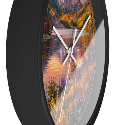 Round wall clock with a black frame and a scenic autumn landscape print featuring a lake, mountains, and colorful wildflowers, shown against a white background.