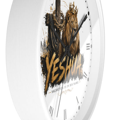 A white round wall clock with a printed religious graphic featuring a crowned lion, a cross with chains, and the word 'YESHUA' in large gold lettering, shown against a plain white background.