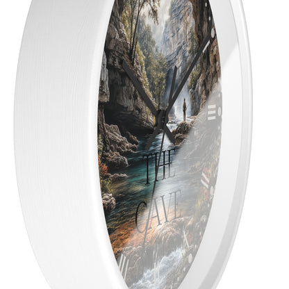 Round wall clock with a white frame and a printed scenic cave interior face, featuring a river, rocky walls, trees, and the words “THE CAVE” in large letters.