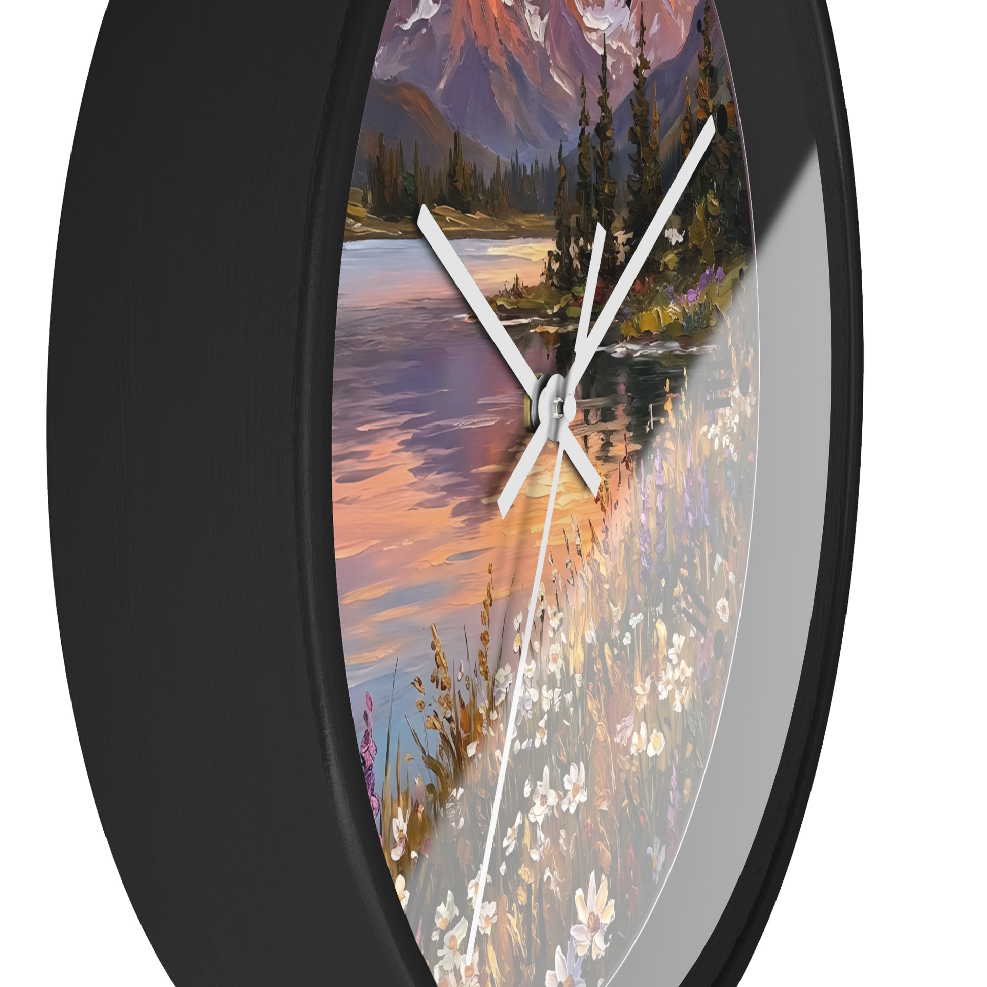 Round wall clock with a black frame and a scenic landscape print featuring a lake, mountains, trees, and wildflowers, shown against a white background.