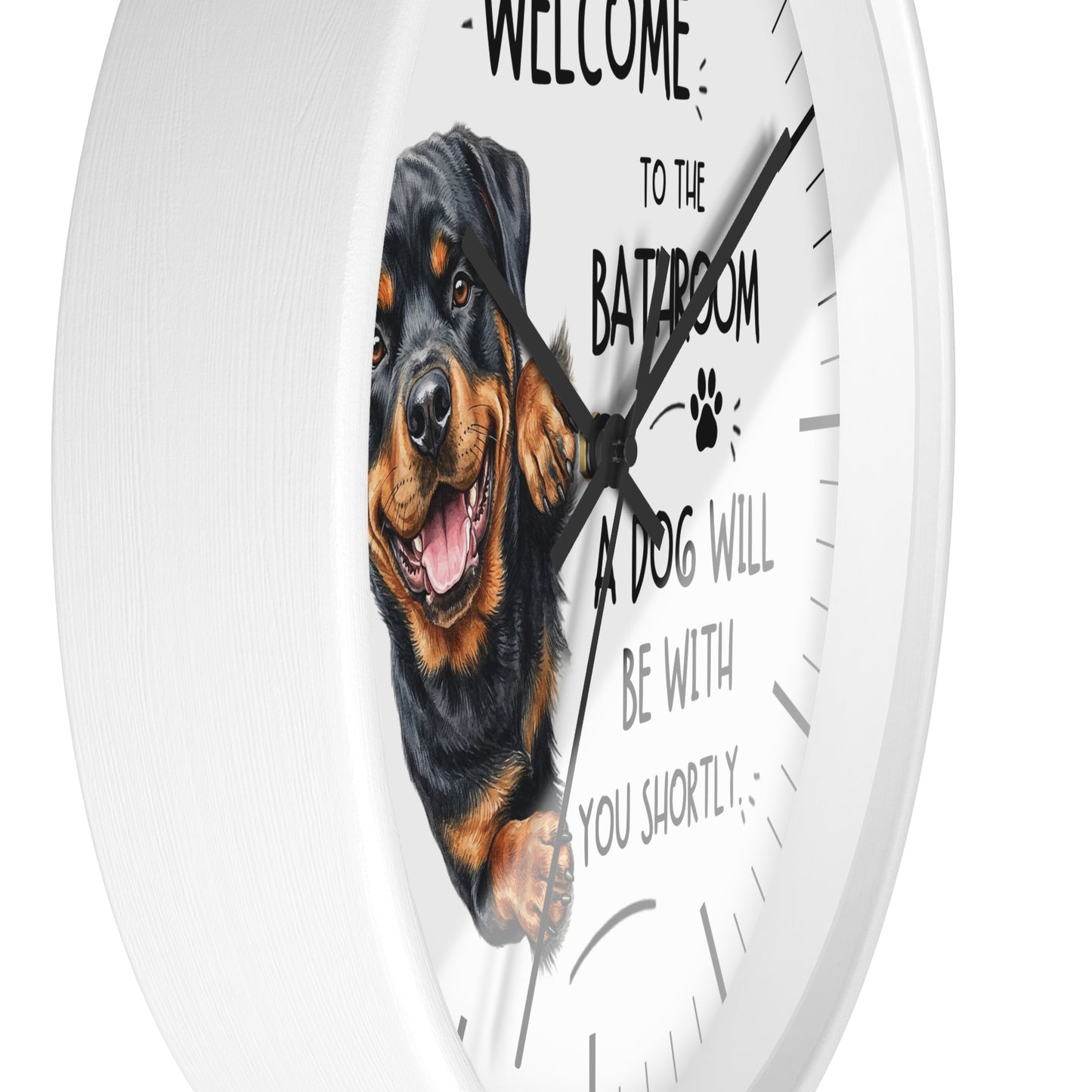 A round white wall clock with a printed graphic of a Rottweiler dog and the humorous text 'WELCOME TO THE BATHROOM A DOG WILL BE WITH YOU SHORTLY' on the face.