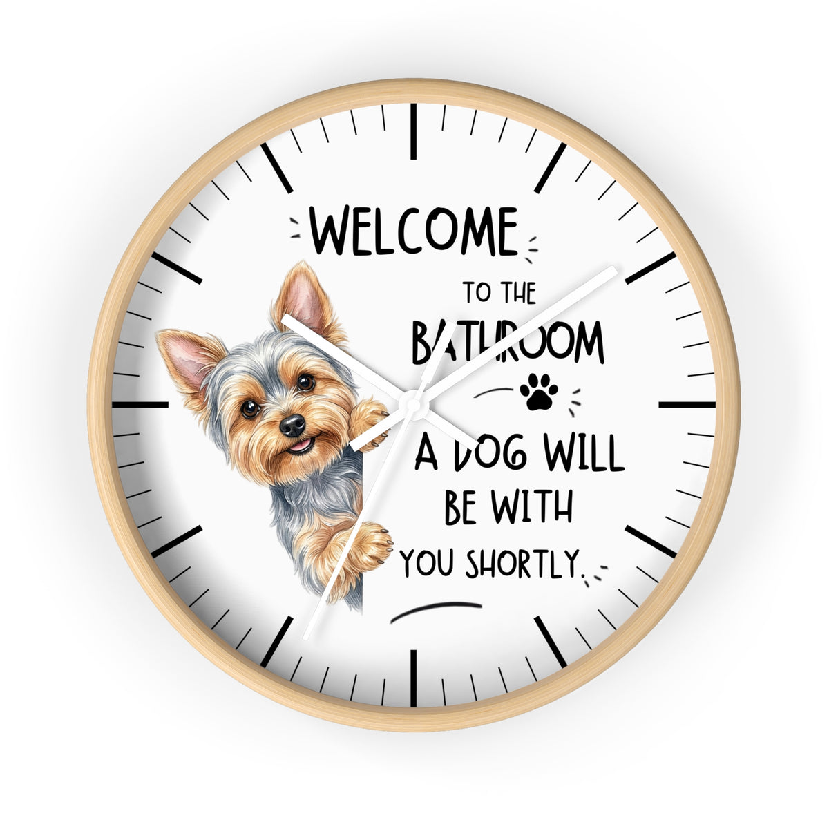 A round wall clock with a light wood frame and a white face, featuring a cartoon illustration of a Yorkshire Terrier and the humorous text 'WELCOME TO THE BATHROOM A DOG WILL BE WITH YOU SHORTLY.' on a plain white background.