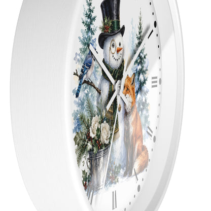 A white round wall clock with a festive winter illustration on the face, featuring a snowman in a black top hat, a bluebird, a fox, evergreen trees, and a bucket of flowers.