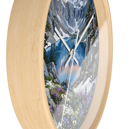 An oval wall clock with a light natural wood frame and a scenic mountain lake print on the face, shown against a plain white background.