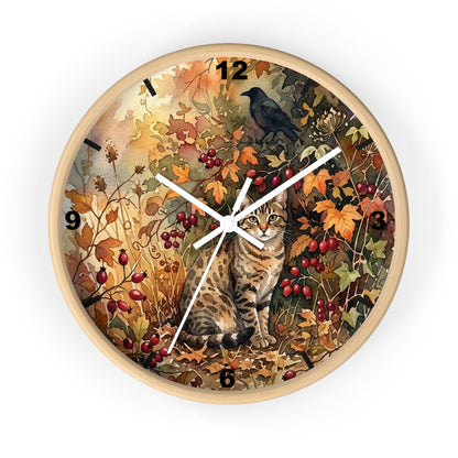 Round wall clock with a light wood frame and a detailed autumn-themed illustration on the face, featuring a tabby cat, a black bird, red berries, and leaves. The clock has black Arabic numerals and white hands.