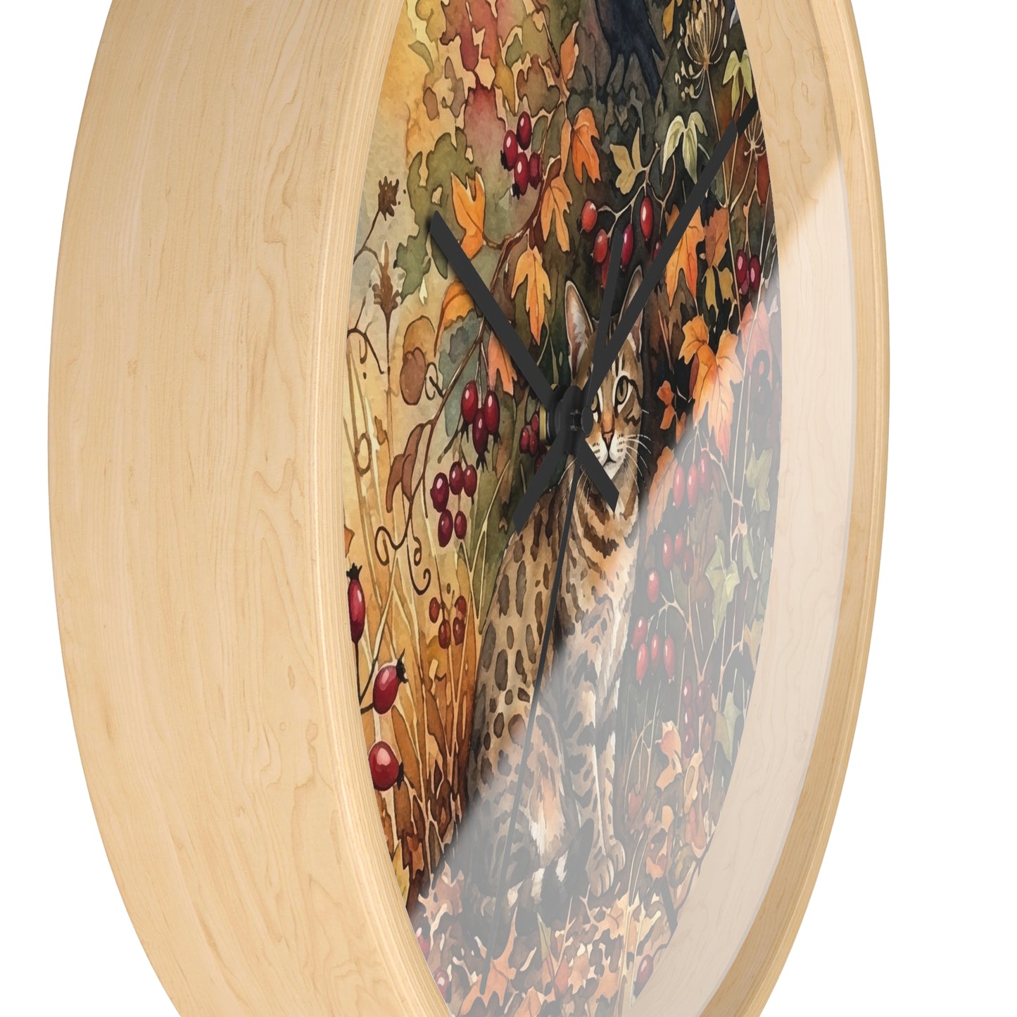 A round wall clock with a light natural wood frame and a printed autumn scene featuring a spotted cat among leaves and red berries, shown against a plain white background.