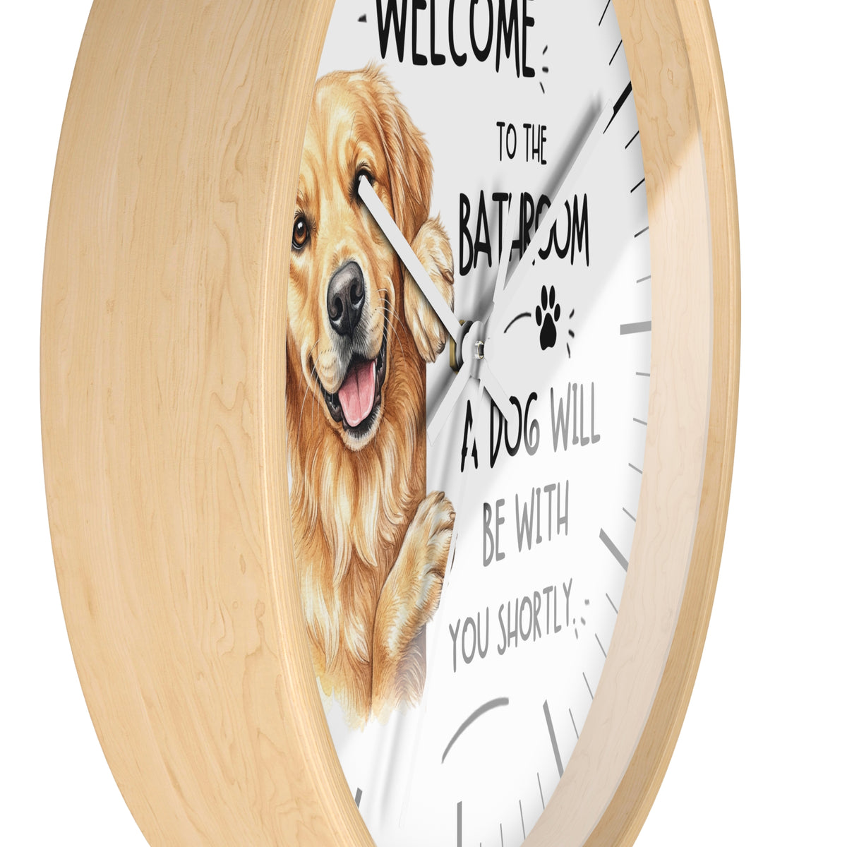 A round wall clock with a light natural wood frame and a white face, featuring a golden retriever illustration and the text 'WELCOME TO THE BATHROOM A DOG WILL BE WITH YOU SHORTLY'.
