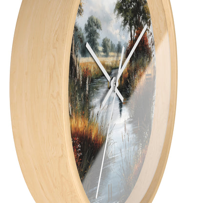 Round wall clock with a light natural wood frame and a scenic landscape print of a stream winding through tall grasses and trees, with white clock hands.