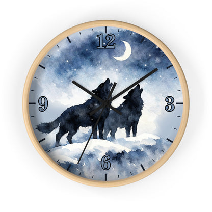 Round wall clock with a light wood frame and a printed night sky dial showing two black wolf silhouettes howling under a crescent moon and stars. The clock has blue-toned watercolor-style graphics, black numerals, and black hands, photographed on a plain white background.