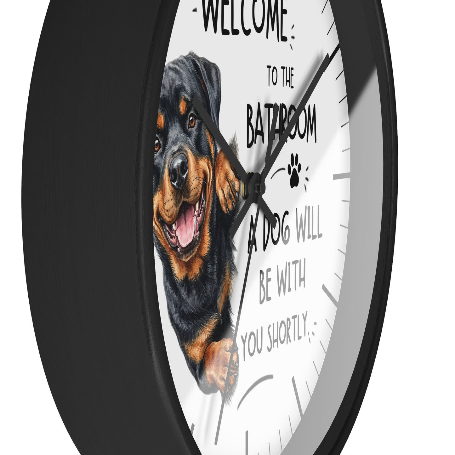 A round wall clock with a black frame and a white face featuring a Rottweiler dog illustration and the text 'WELCOME TO THE BATROOM A DOG WILL BE WITH YOU SHORTLY'.