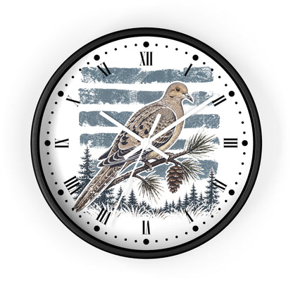 A round wall clock with a black frame and a white face featuring a detailed illustration of a brown dove bird perched on a pine branch, with blue-gray brushstroke stripes and a forest silhouette at the bottom.