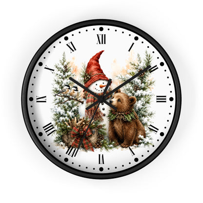 A round wall clock with a black frame and a white face featuring a winter holiday illustration of a snowman in a red hat, a brown bear, evergreen trees, and Roman numerals.