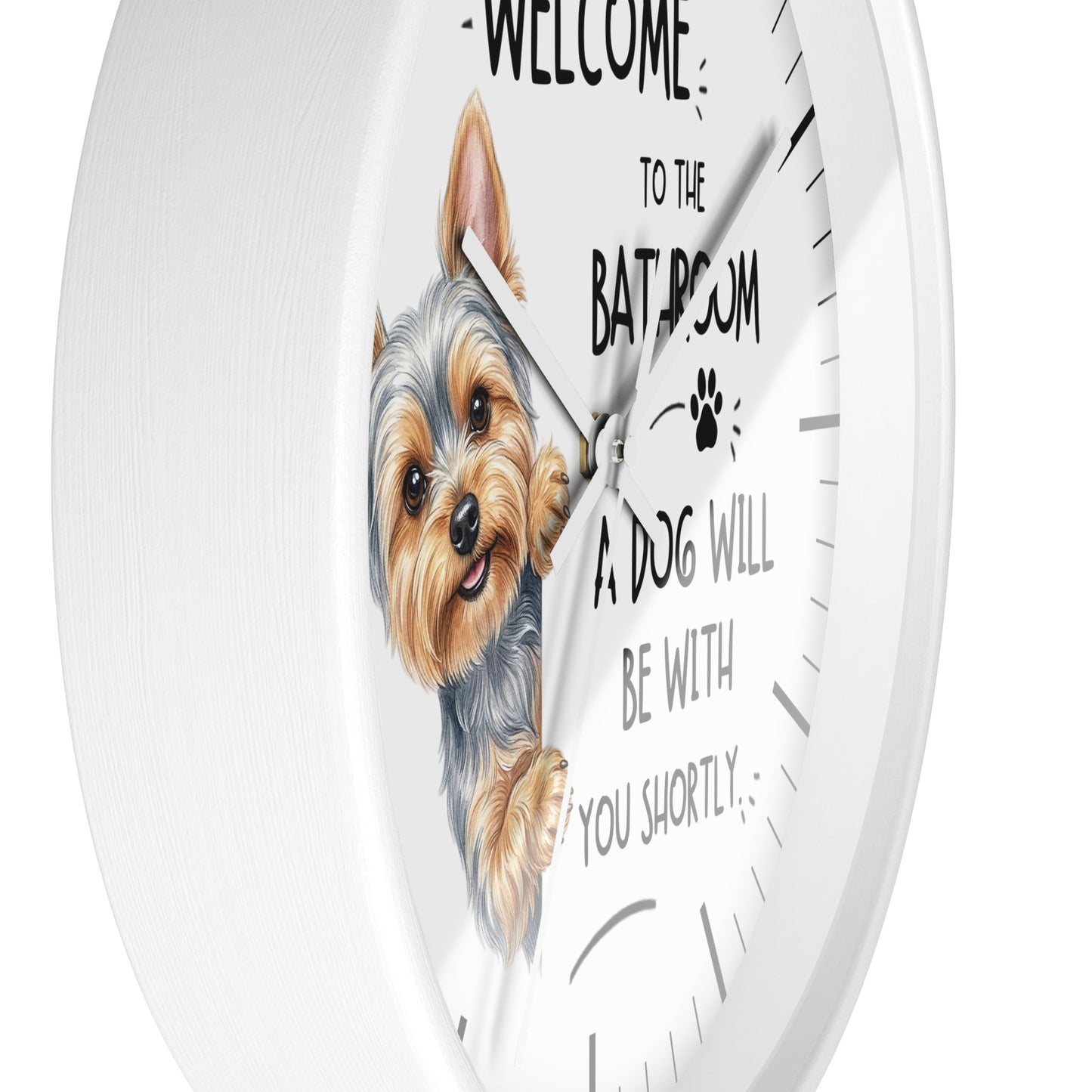 A white round wall clock with a printed illustration of a small dog and the text 'WELCOME TO THE BATHROOM A DOG WILL BE WITH YOU SHORTLY' on a clean white background.