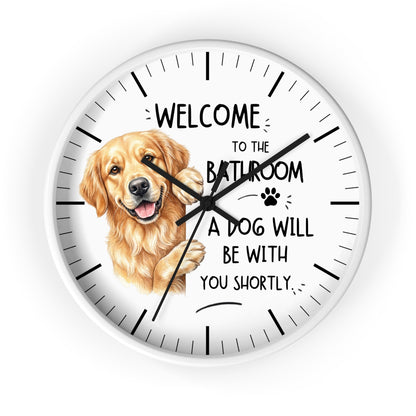 A round white wall clock with black hands and hour markers, featuring a golden retriever illustration and the text 'WELCOME TO THE BATHROOM A DOG WILL BE WITH YOU SHORTLY' on a white background.