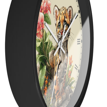 A close-up of a round wall clock with a black frame and a cream-colored face featuring an illustrated leopard cub surrounded by pink flowers and green leaves.
