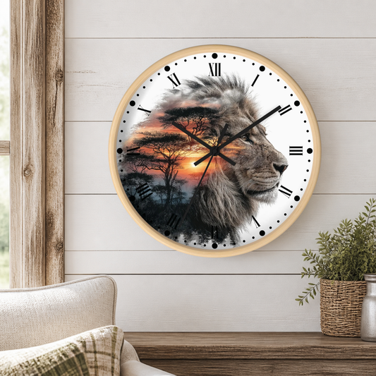 A round wall clock with a light wood frame hangs on a white shiplap wall above a wooden table. The clock face features a photographic lion profile layered over a savanna sunset scene with acacia trees.