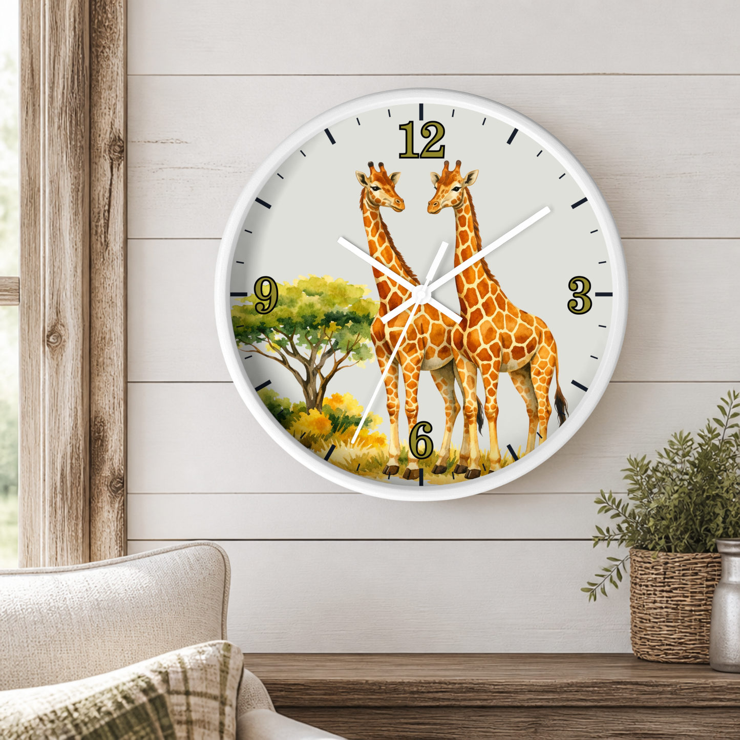 A round wall clock with a white frame and a safari design featuring two giraffes, displayed on a light wood-paneled wall above a wooden shelf with a small potted plant.