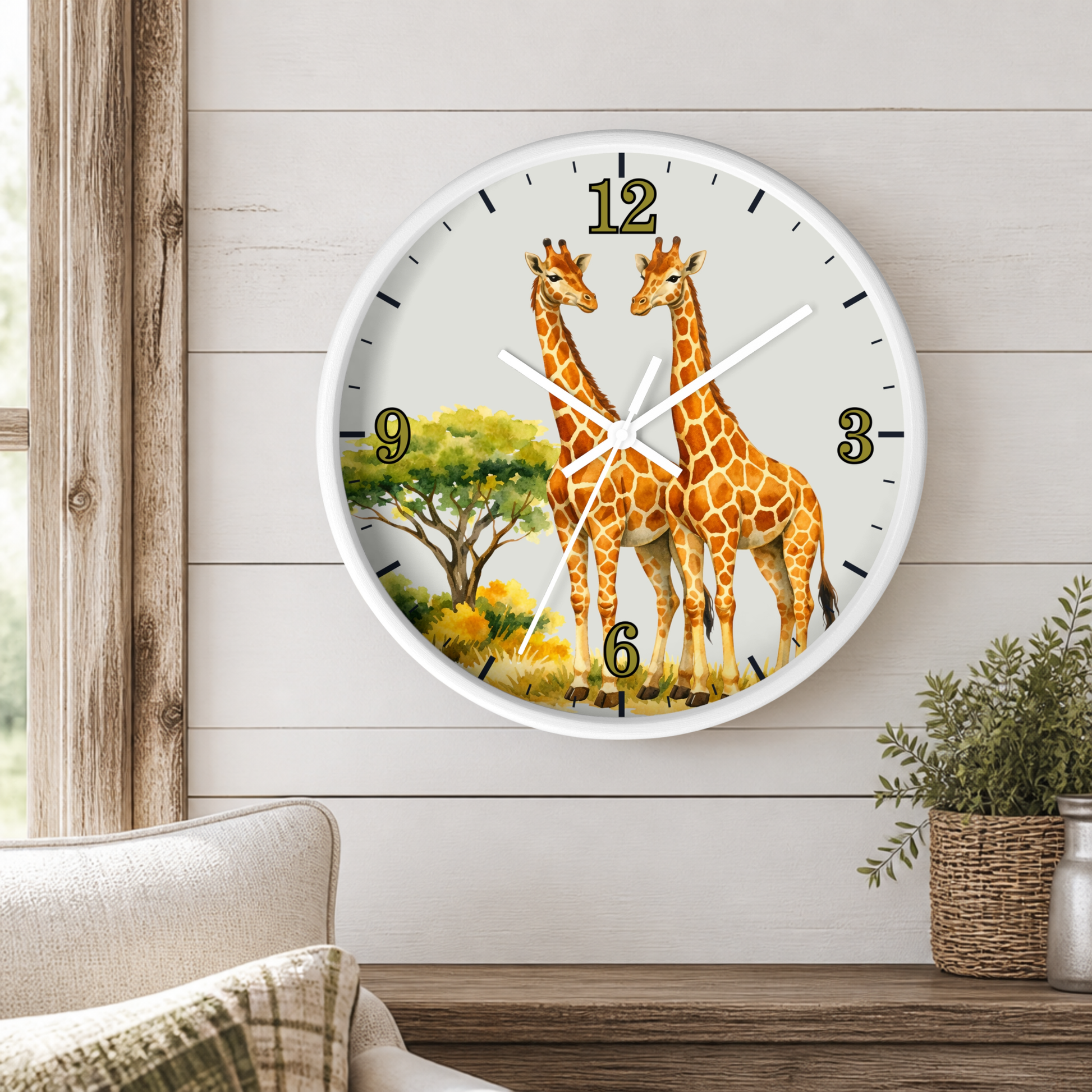 A round wall clock with a white frame and a safari design featuring two giraffes, displayed on a light wood-paneled wall above a wooden shelf with a small potted plant.