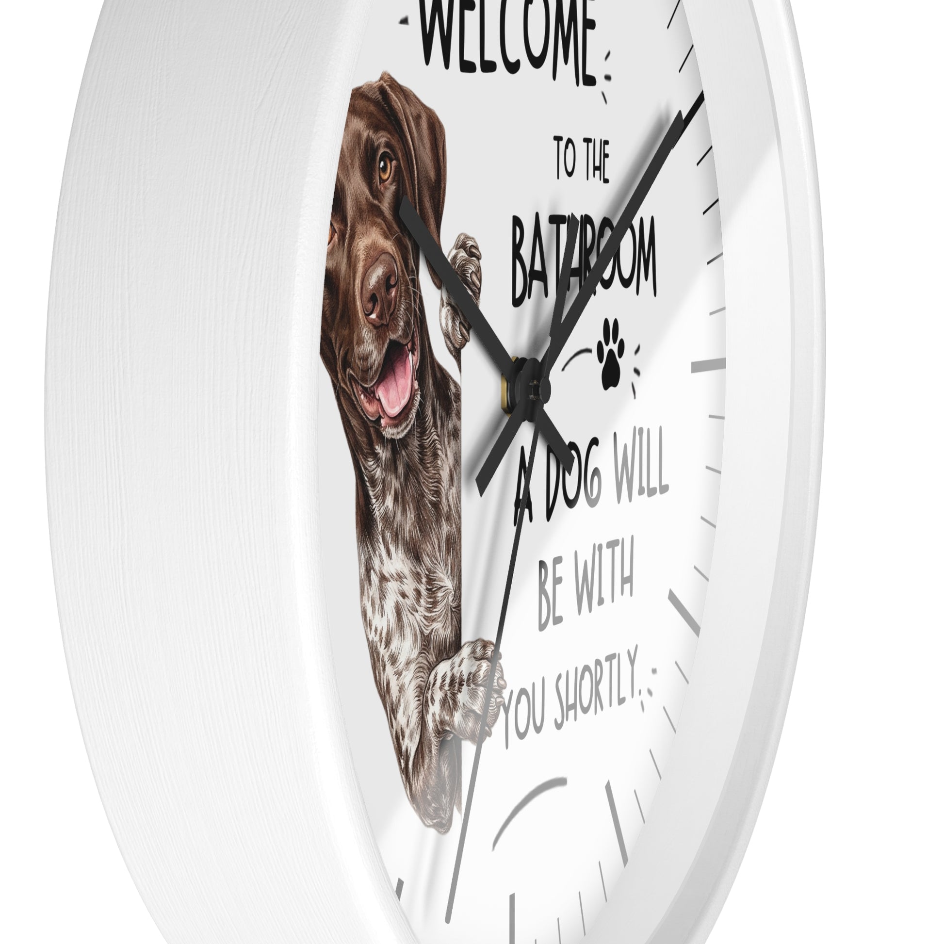 A round white wall clock with a humorous pet message that reads 'WELCOME TO THE BATROOM A DOG WILL BE WITH YOU SHORTLY' alongside a graphic of a German shorthaired pointer dog. The clock is shown mounted on a white wall.