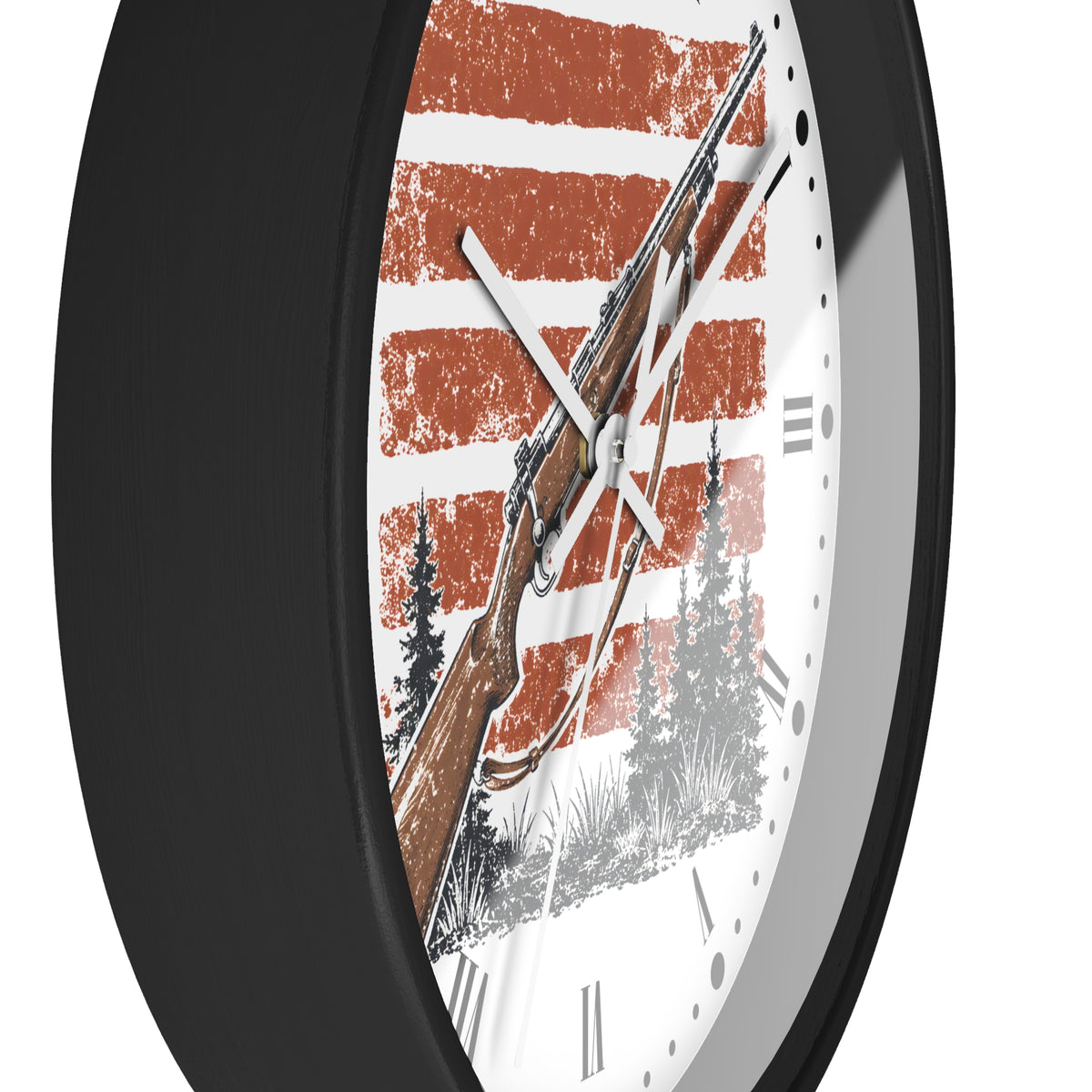 A close-up of a round wall clock with a black frame and a white face featuring a rustic orange and white striped design, a brown rifle illustration, and black tree silhouettes.