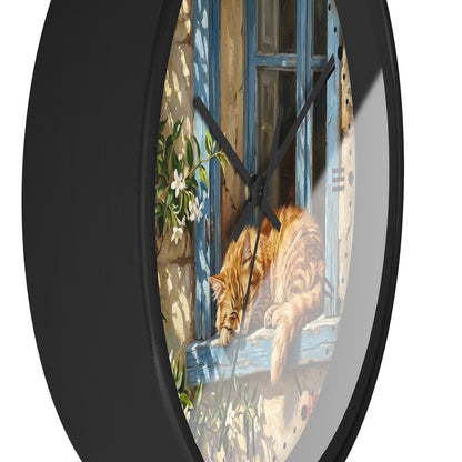 Round wall clock with a black frame and a printed illustration of an orange tabby cat resting on a blue window sill.