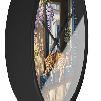 Round wall clock with a black frame and a printed illustration of an orange tabby cat sleeping on a windowsill, with purple wisteria and a sunlit balcony scene.
