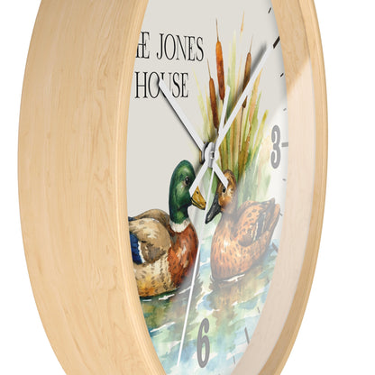 A round wall clock with a light natural wood frame and a printed dial showing two ducks, cattails, and the text 'THE JONES HOUSE' on a white background.
