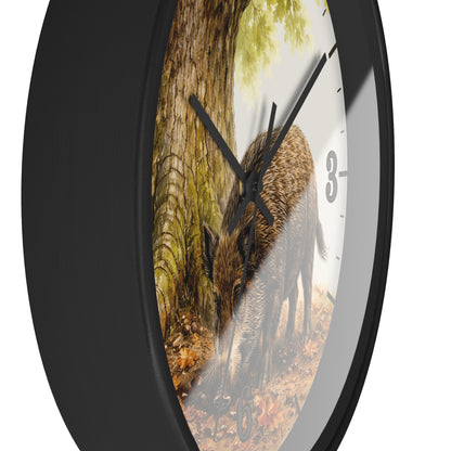 A round wall clock with a black frame and a printed nature scene on the face showing a wild boar in a forest, photographed against a plain white background.