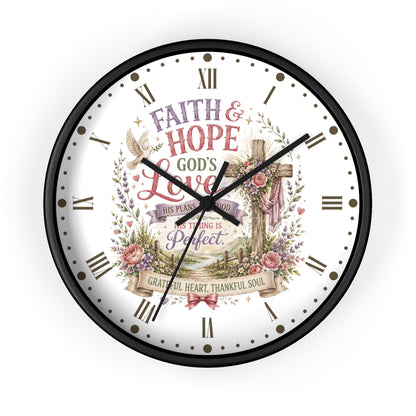 A round wall clock with a black frame and a white face featuring a religious illustration and the words 'FAITH & HOPE GOD'S LOVE THIS PLAN IS GOOD TOUGHING IS Perfect GRATEFUL HEART THANKFUL SOUL' with Roman numerals and black hands.