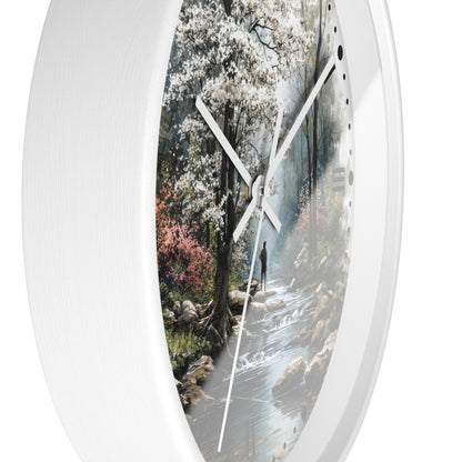 A round wall clock with a white textured frame and a printed scenic dial showing a forest stream with white blossoms, photographed against a plain white background.