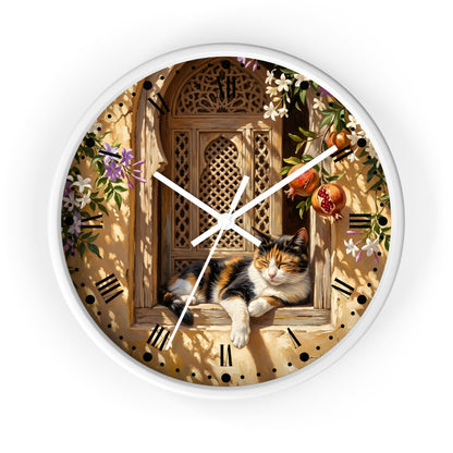 A round wall clock with a white frame and hands, featuring a printed design of a calico cat resting on a wooden window ledge with flowers, pomegranates, and a warm beige background.