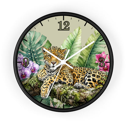 A round wall clock with a black frame and a tropical jungle design featuring a leopard, palm leaves, and flowers. The clock face has a beige background with black Arabic numerals and white clock hands.