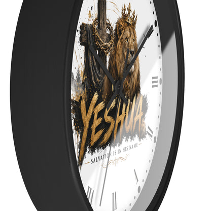 A round wall clock with a black frame and a white face featuring a crowned lion, a wooden cross with a crown of thorns, and the word 'YESHUA' in large gold lettering.