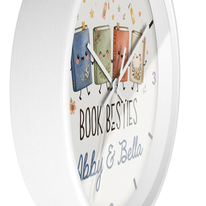 A round white wall clock with a whimsical illustration of four smiling book characters and the text 'BOOK BESTIES Abby & Bella' on the clock face.