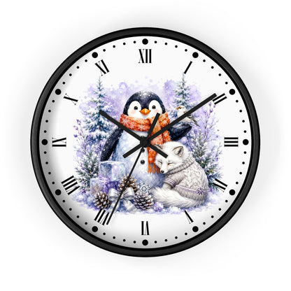 A round wall clock with a black frame and a white face featuring a winter illustration of a penguin in an orange scarf, a white fox, pine trees, and snow. The clock has black Roman numerals and black hands on a plain white background.