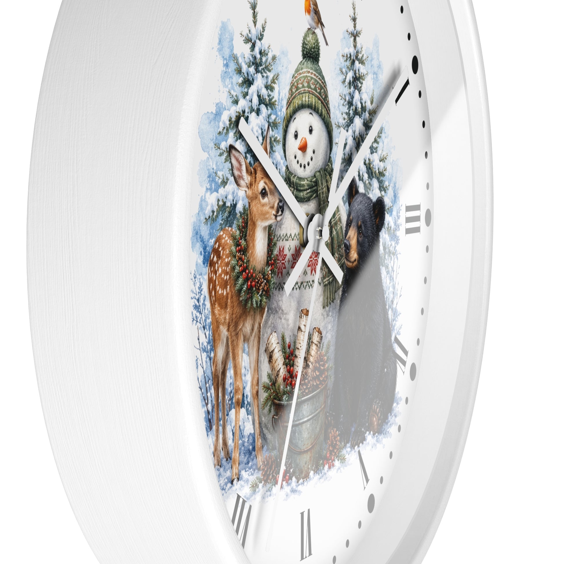 A white round wall clock with a winter woodland illustration on the face, featuring a snowman in a green hat, a deer with a wreath, a bear, snowy trees, and a bird feeder. The clock is shown against a plain white background.