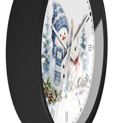 A round wall clock with a black frame and a white face featuring a winter holiday illustration of a snowman in a blue knit hat and scarf next to a white rabbit with a red bow tie, set against a snowy background.