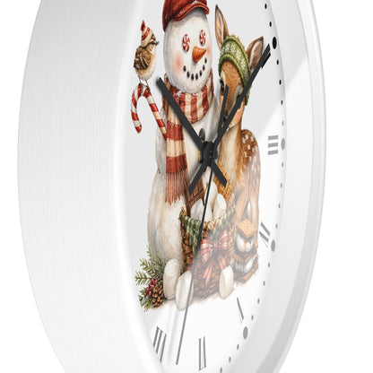 A round white wall clock featuring a festive winter illustration of a snowman in a red hat and scarf holding a candy cane, next to a deer wearing a green knit hat, with black Roman numerals on a white face.