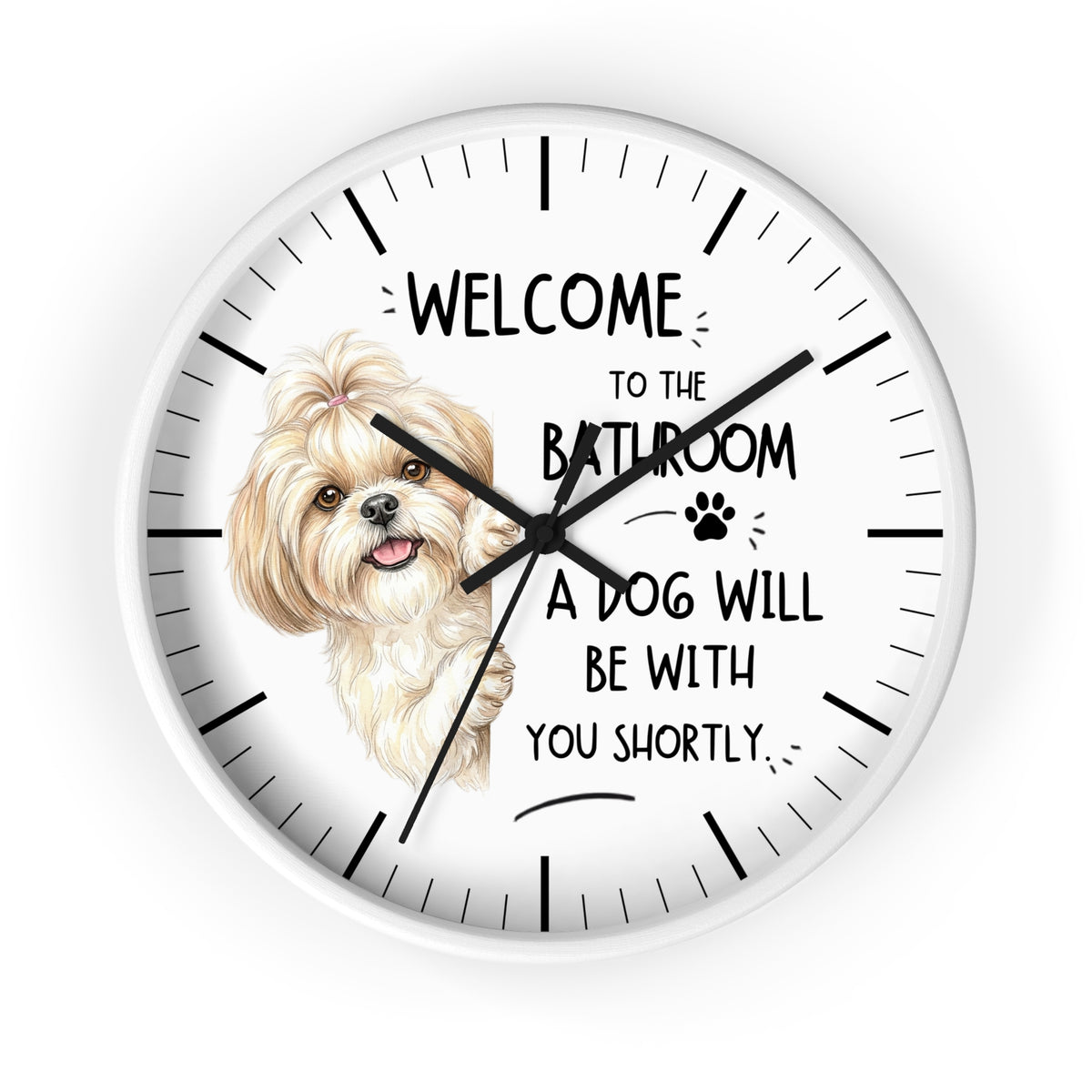A round wall clock with a white face, black hands, black hour markers, and a printed illustration of a small fluffy dog next to the text 'WELCOME TO THE BATHROOM A DOG WILL BE WITH YOU SHORTLY.' on a light gray background.