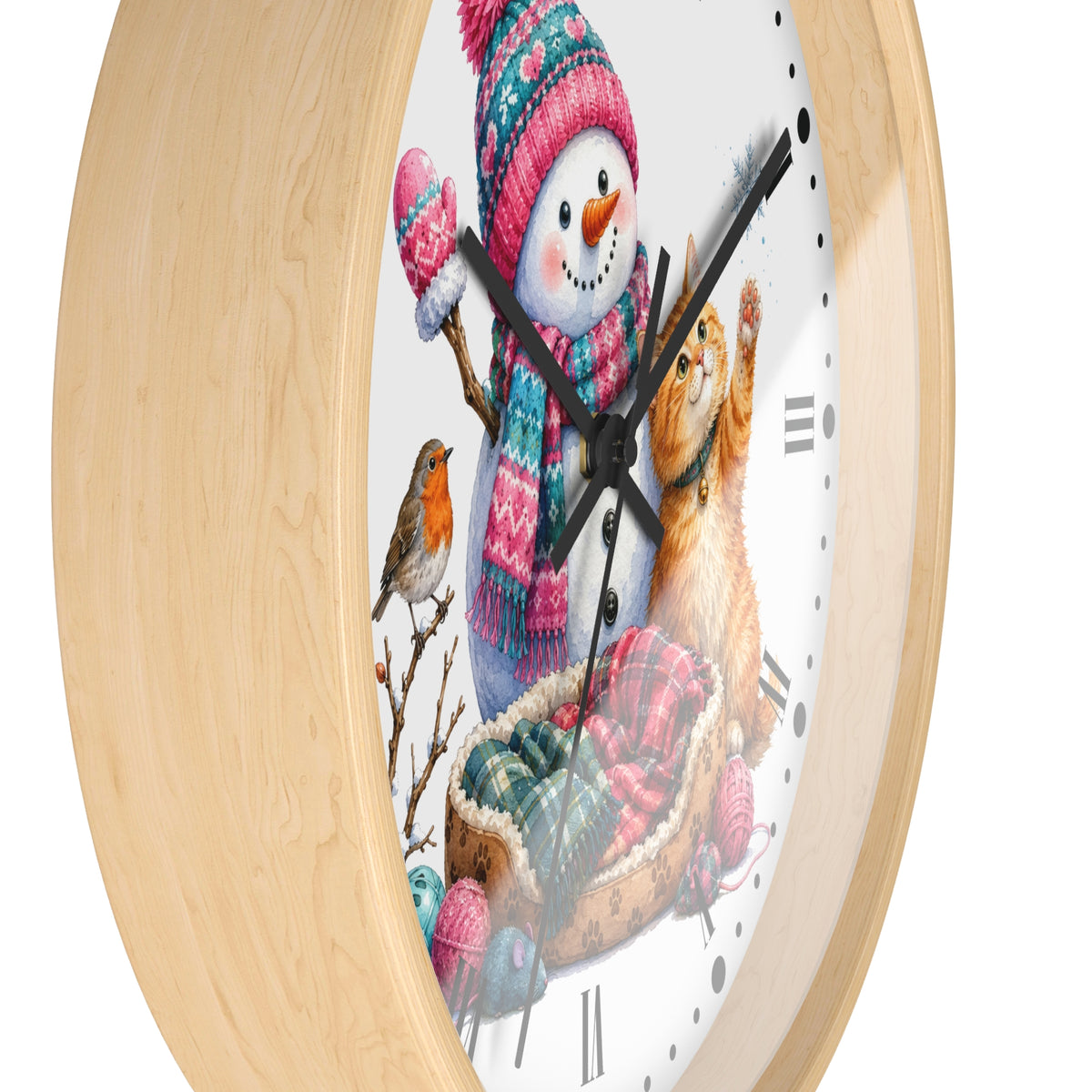 A round wall clock with a light natural wood frame and a white face featuring a winter illustration of a snowman, a cat, a bird, and a sled. The clock is shown cropped at an angle against a plain white background.