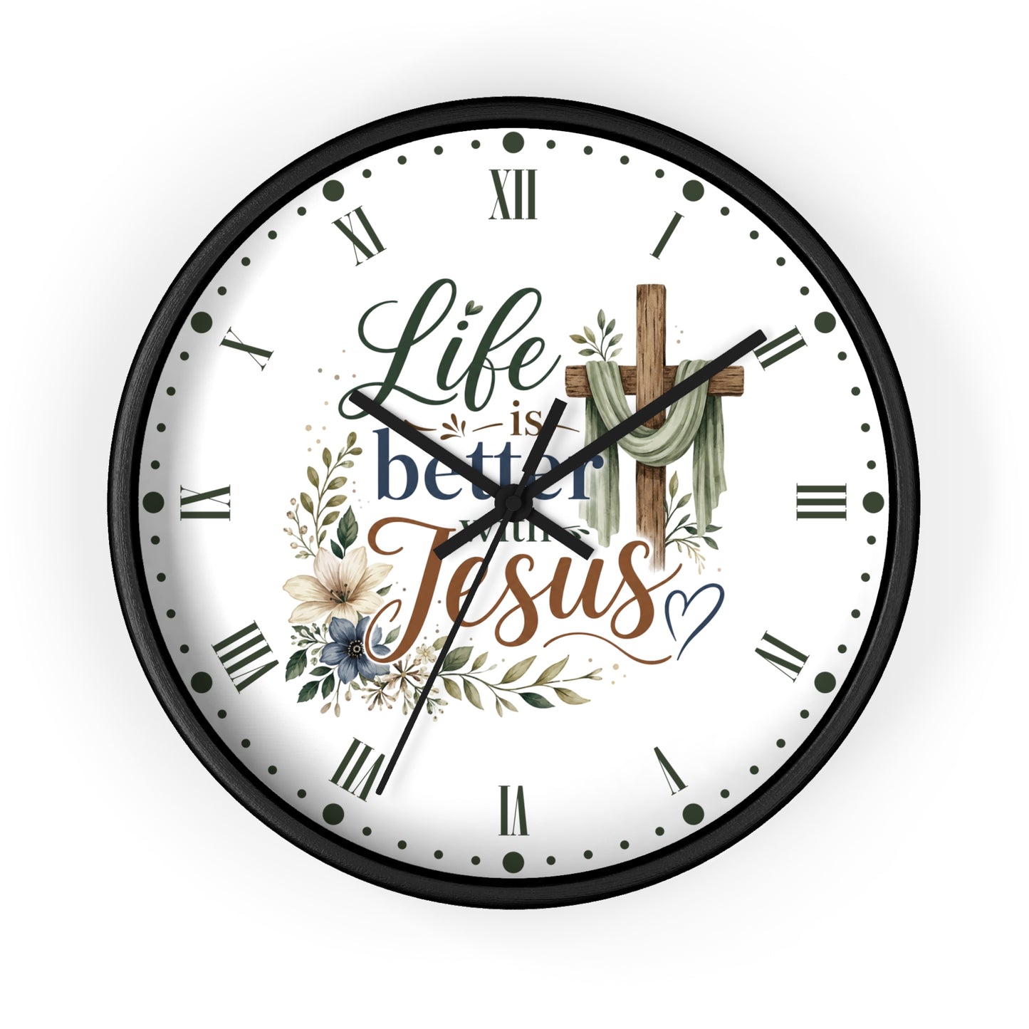 A round wall clock with a black frame and a white face featuring the text 'Life is better with Jesus' in decorative script, Roman numerals, floral illustrations, and a wooden cross.