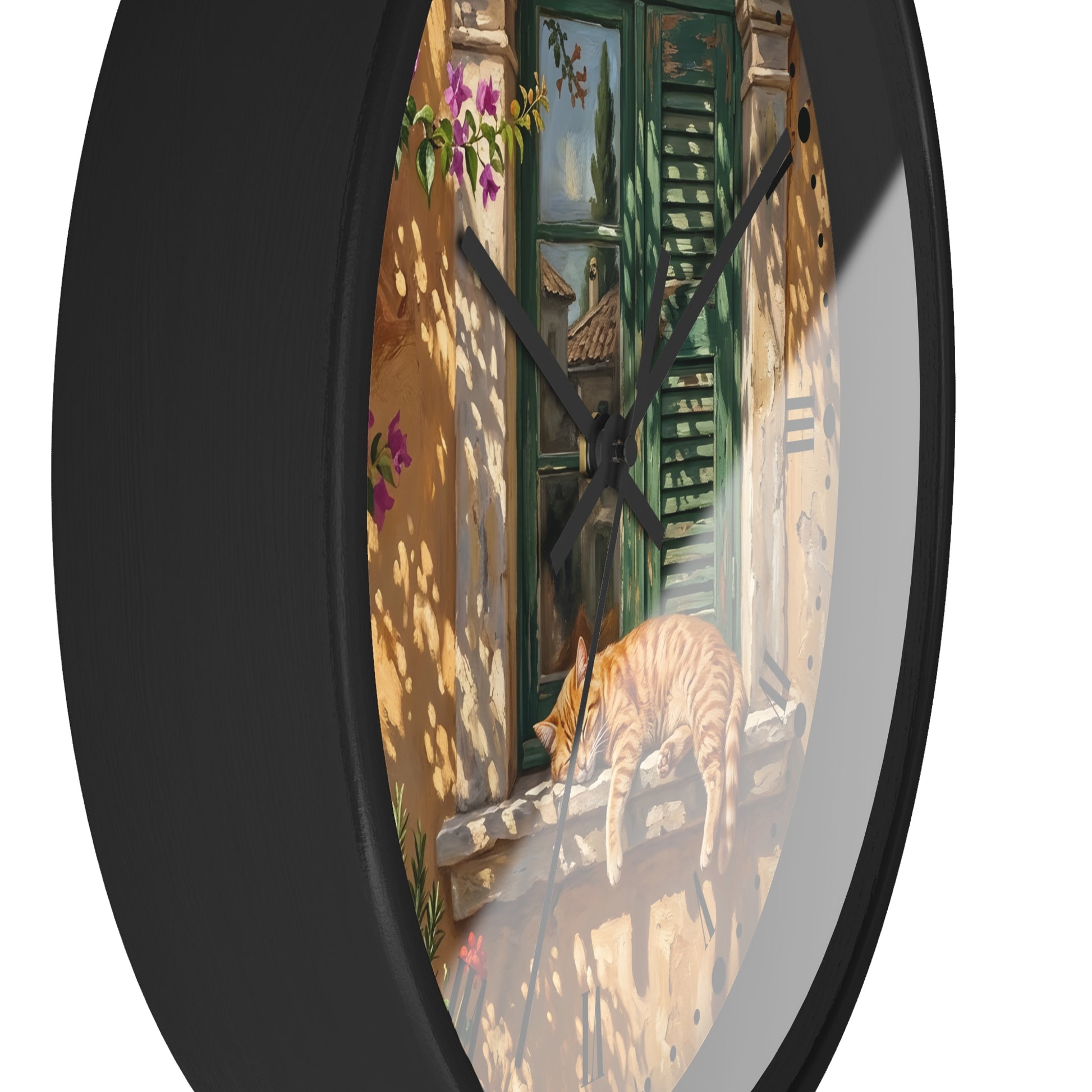 Round wall clock with a black frame and a printed scenic face showing a sunlit courtyard with green shutters, flowers, and an orange tabby cat on a windowsill.