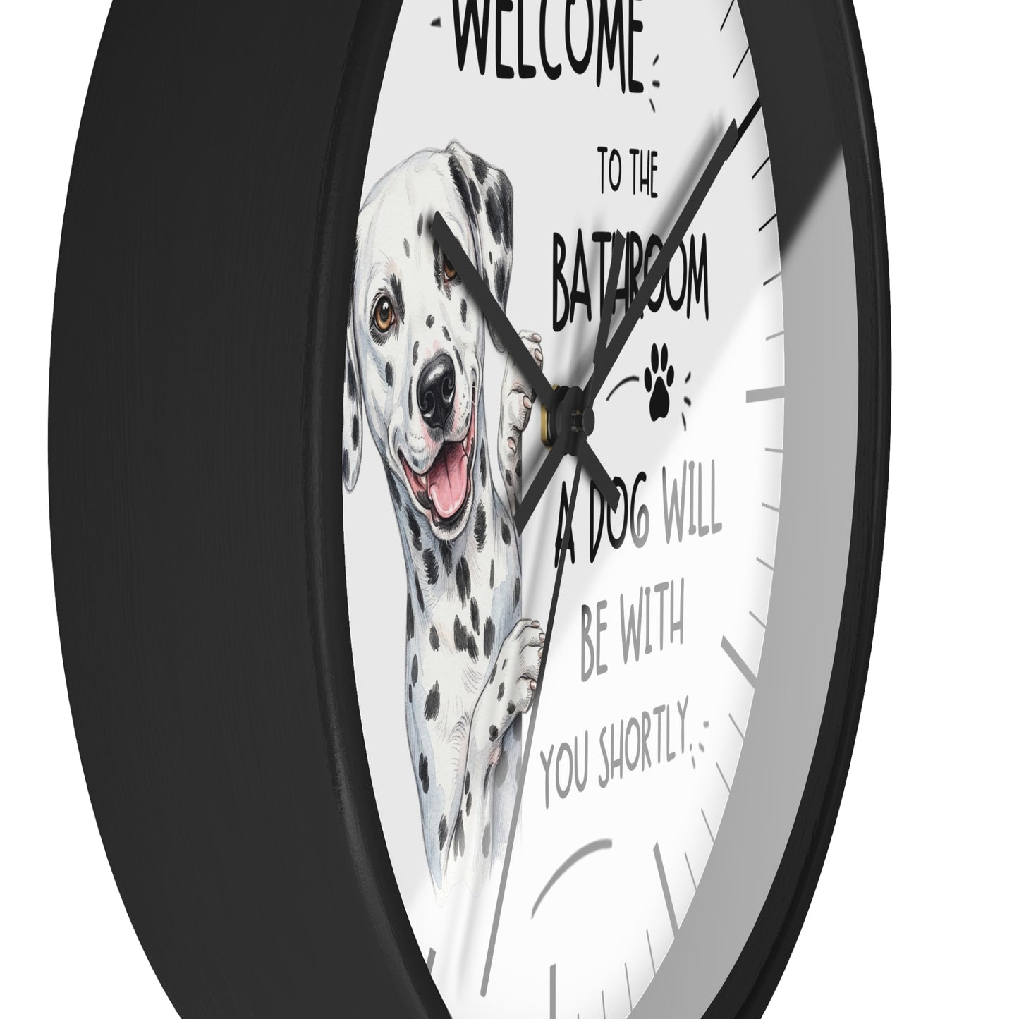 A round wall clock with a black frame and a white face featuring a Dalmatian illustration and the text 'WELCOME TO THE BATHROOM A DOG WILL BE WITH YOU SHORTLY'.