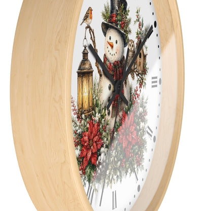 A round wall clock with a light natural wood frame and a white face featuring a festive winter illustration of a snowman, red poinsettias, green foliage, a lantern, and a small bird.